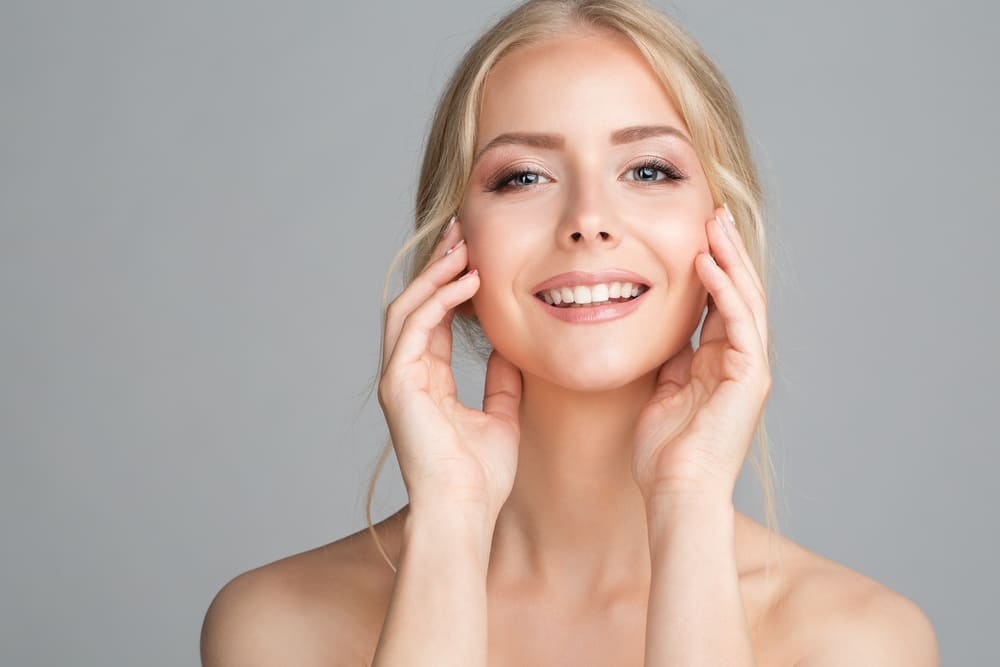 Cheerful Smiling Young Woman Massaging Face Cheek Bones