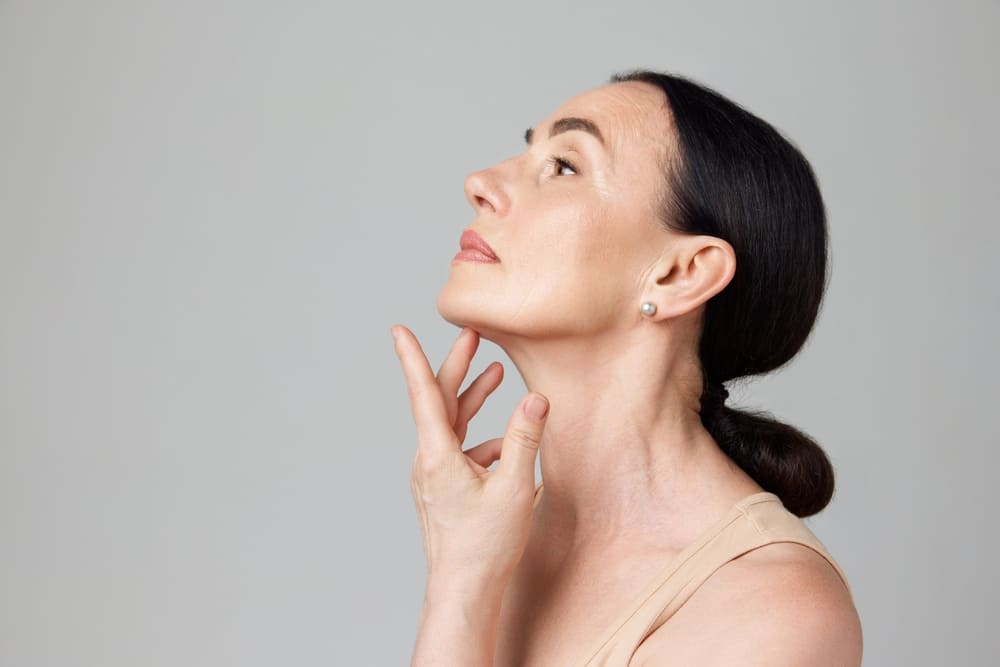 Double chin treatment. Beautiful mature woman touching skin on neck