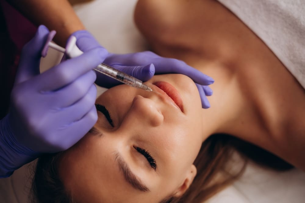 Professional female beautician makes a rejuvenating injection to a young woman
