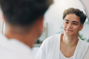 Happy man, mirror and check for cleaning in home with results, face reflection and grooming in morning