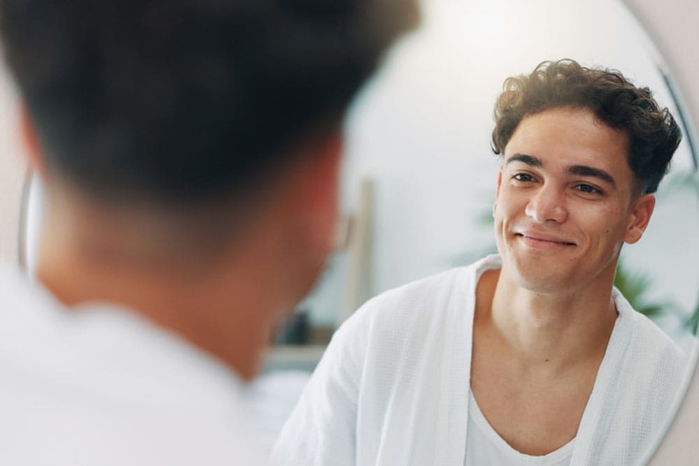 Happy man, mirror and check for cleaning in home with results, face reflection and grooming in morning