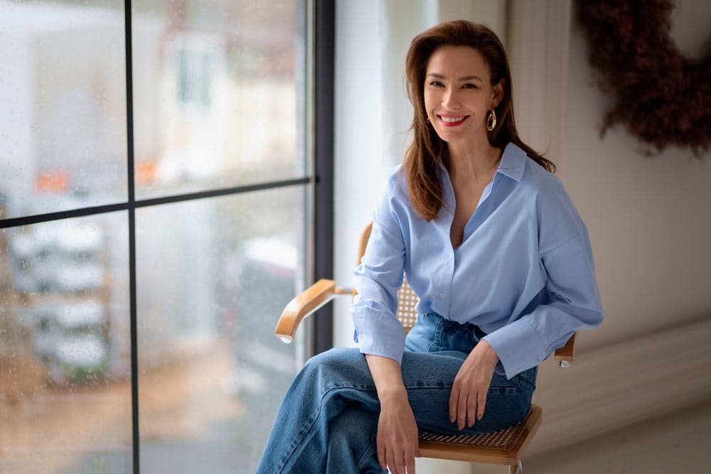 Happy mature woman relaxing on chair, enjoying peaceful moment in cozy home environment.