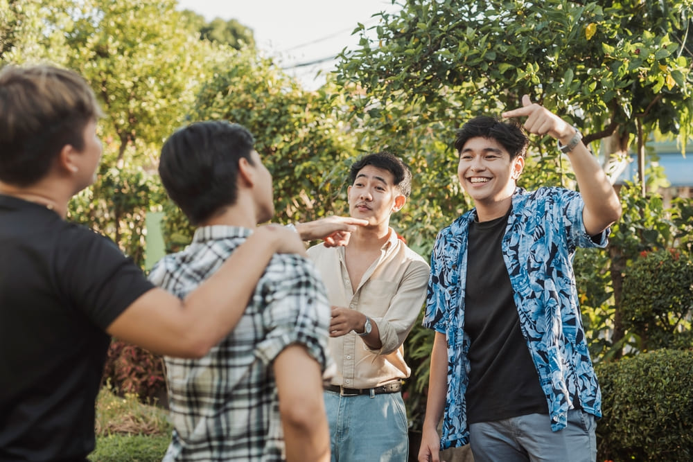 A confident young Southeast Asian man points at a friend with a big smile